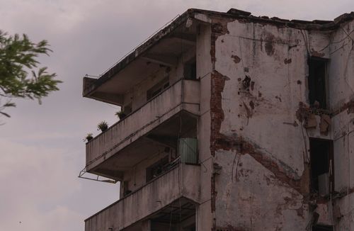 Free A worn, old building with cracked walls and balconies under a grey sky. Stock Photo