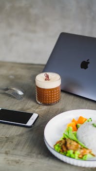 Minimalist workspace featuring a laptop, coffee, and smartphone on a concrete table.
