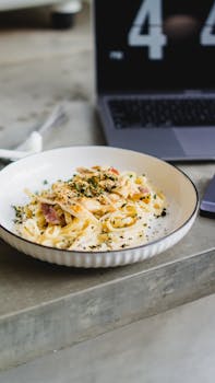 A mouth-watering plate of creamy fettuccine alfredo garnished with herbs.