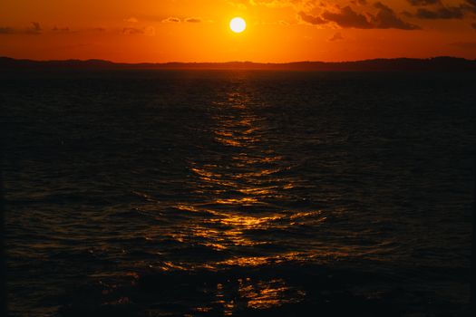 A breathtaking view of the sun setting over the ocean, casting golden reflections on the water.