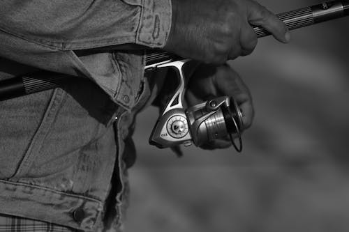 Grayscale Photo of Person Holding a Fishing Rod