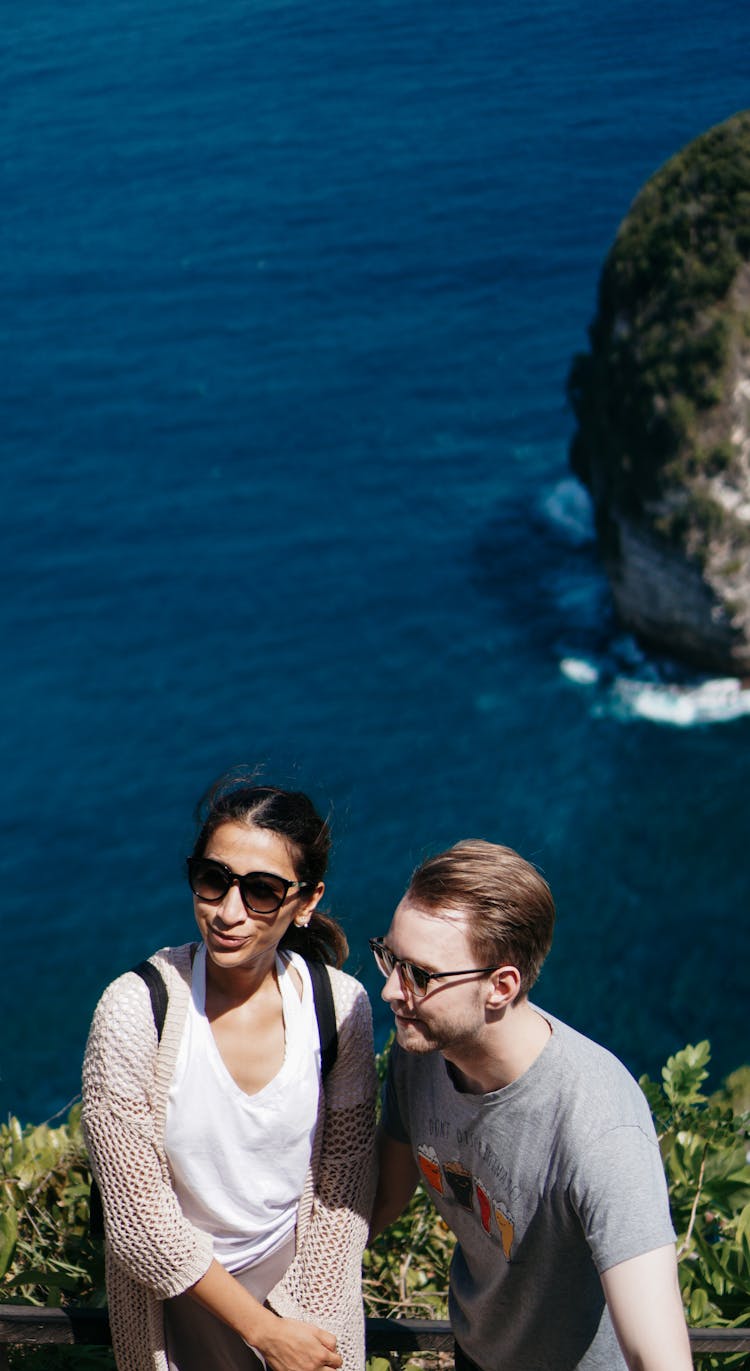 Man And Woman Standing On A Cliff Near Beach