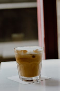A creamy cappuccino served in a glass on a table at a cozy cafe in Istanbul, Turkey.