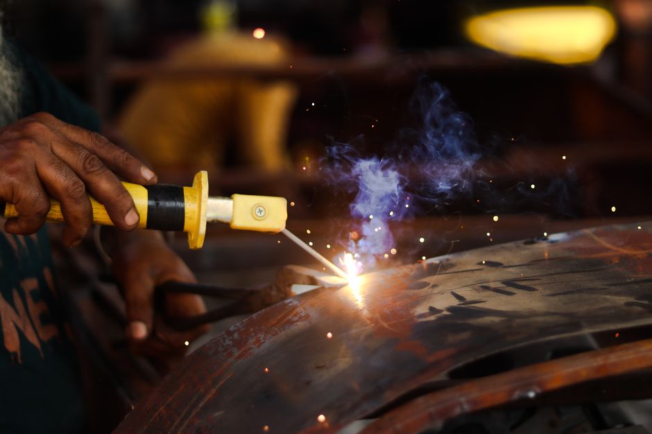 Close-up of a welder in action, creating sparks while working on metal indoors.