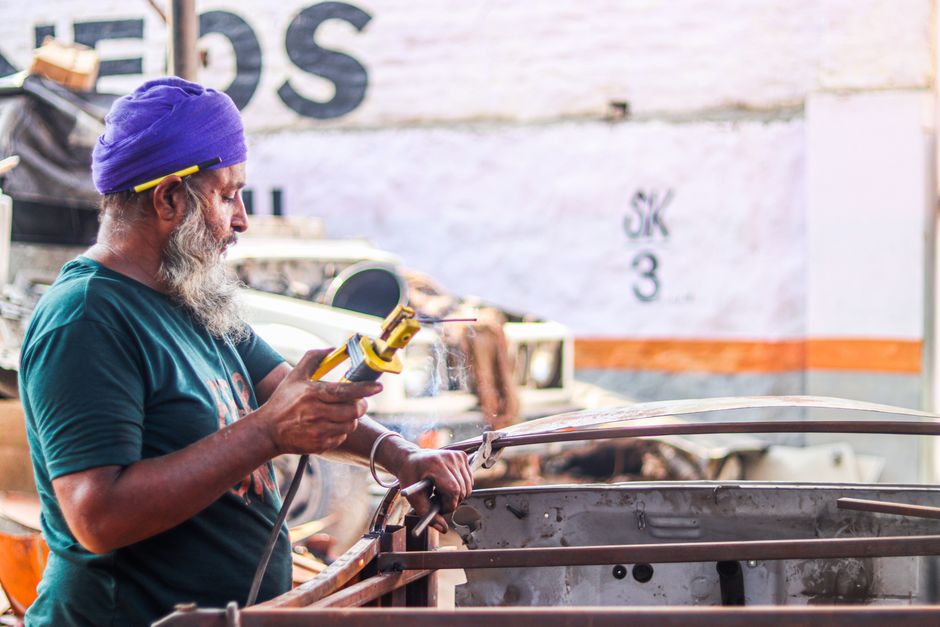 Experienced welder working on metal fabrication in a sunlit workshop.