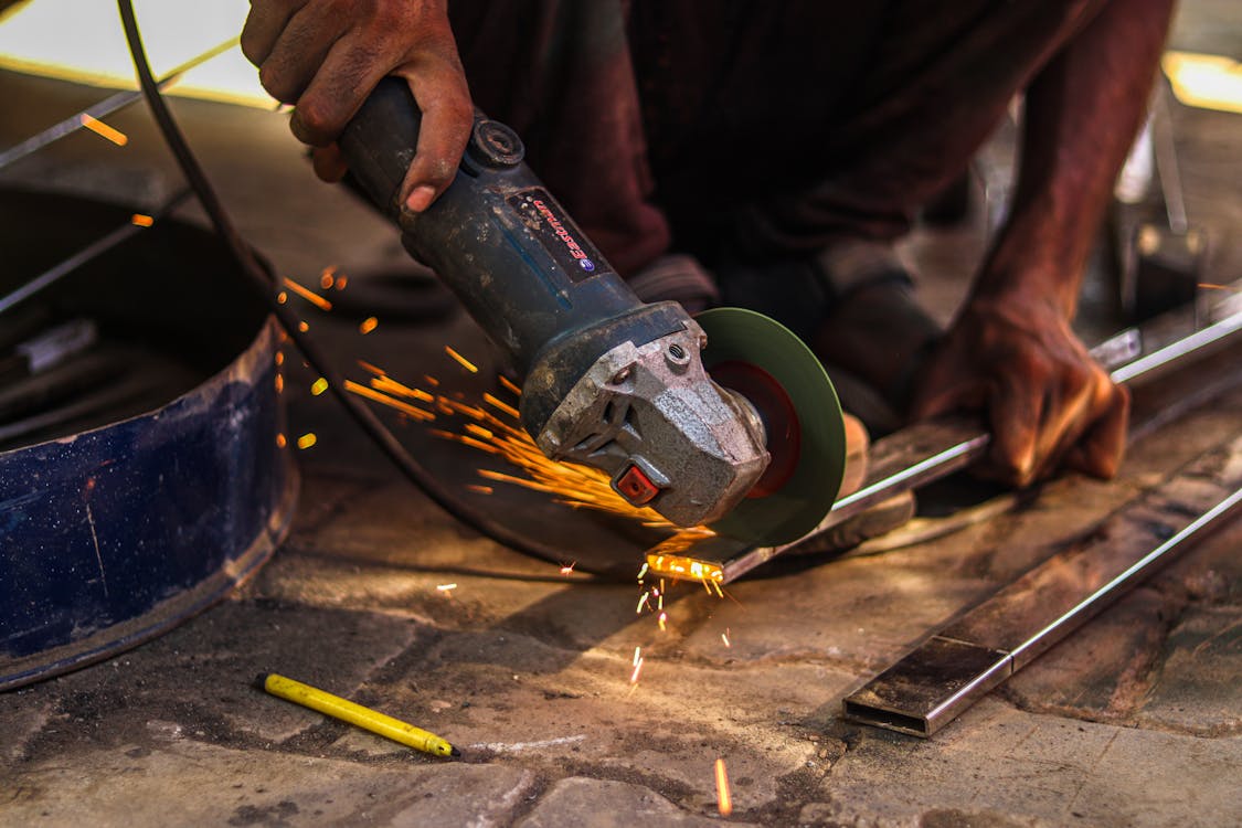 A Man Grinding Steel Using an Angle Grinder