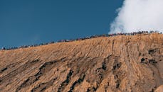 晴朗的蓝天下，一大群人沿着崎岖的山脊徒步旅行
