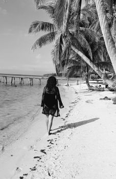 Woman walking along the palm-lined shore in Phú Quốc, Vietnam. Black and white elegance.