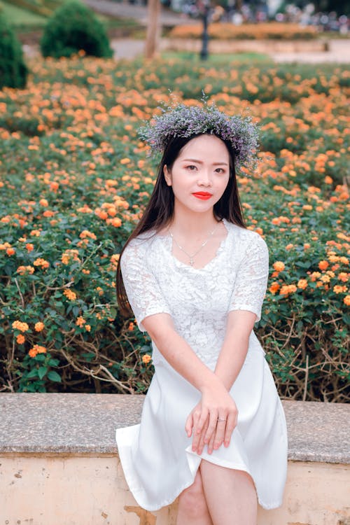 Selective Focus Photography of Woman Sitting on Concrete Near of Orange Flower Field