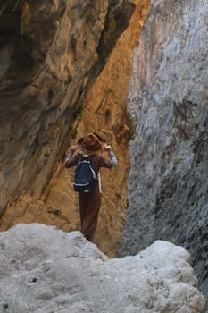 Woman exploring a rugged canyon with a backpack, embracing outdoor adventure.