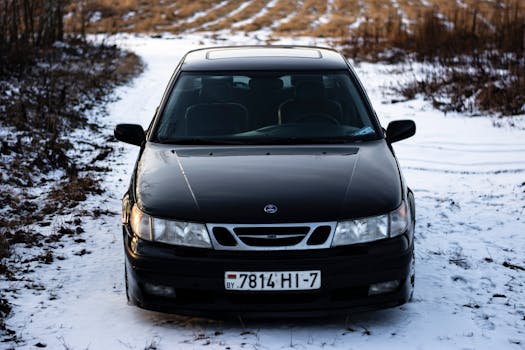 Close-up of a black car parked on a snow-covered road during winter, offering a striking contrast.