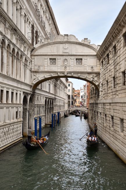 Gondolas glide under the iconic Bridge of Sighs in Venice, Italy's enchanting canals.