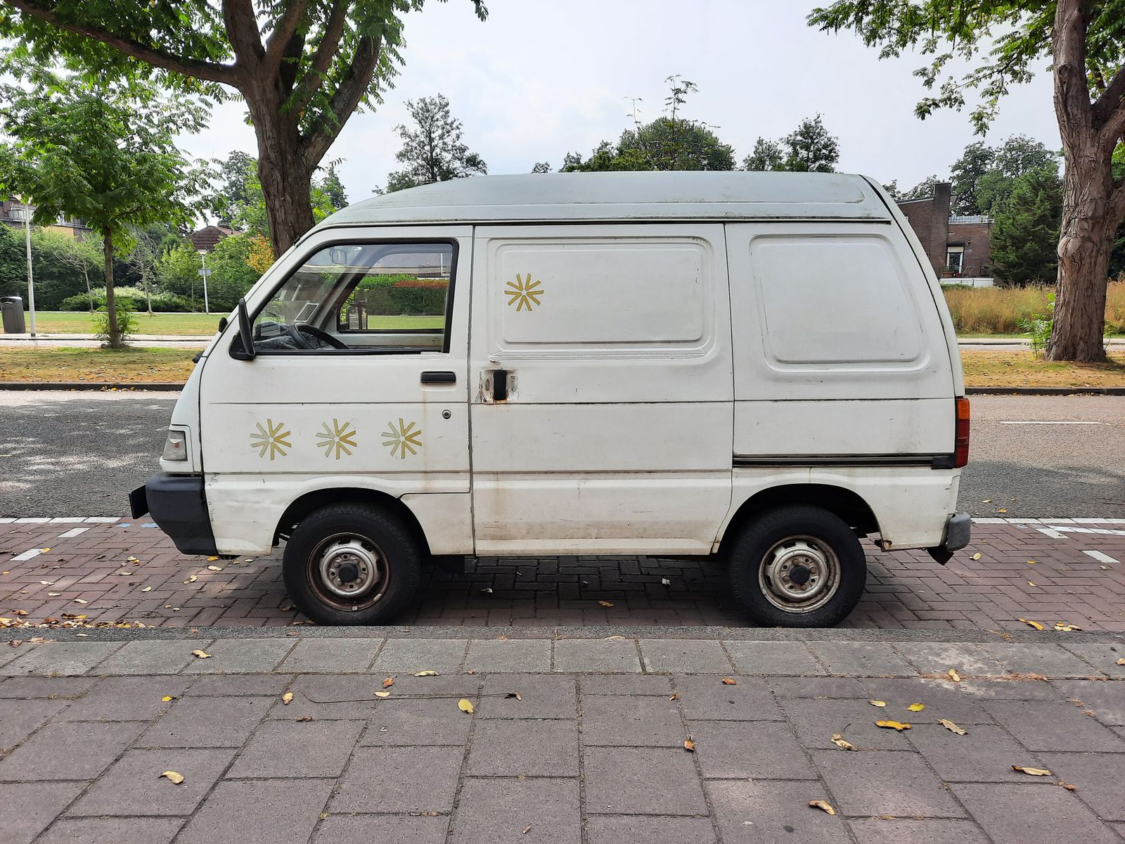 Fourgonnette utilitaire blanche sans inscription garée dans une rue arborée