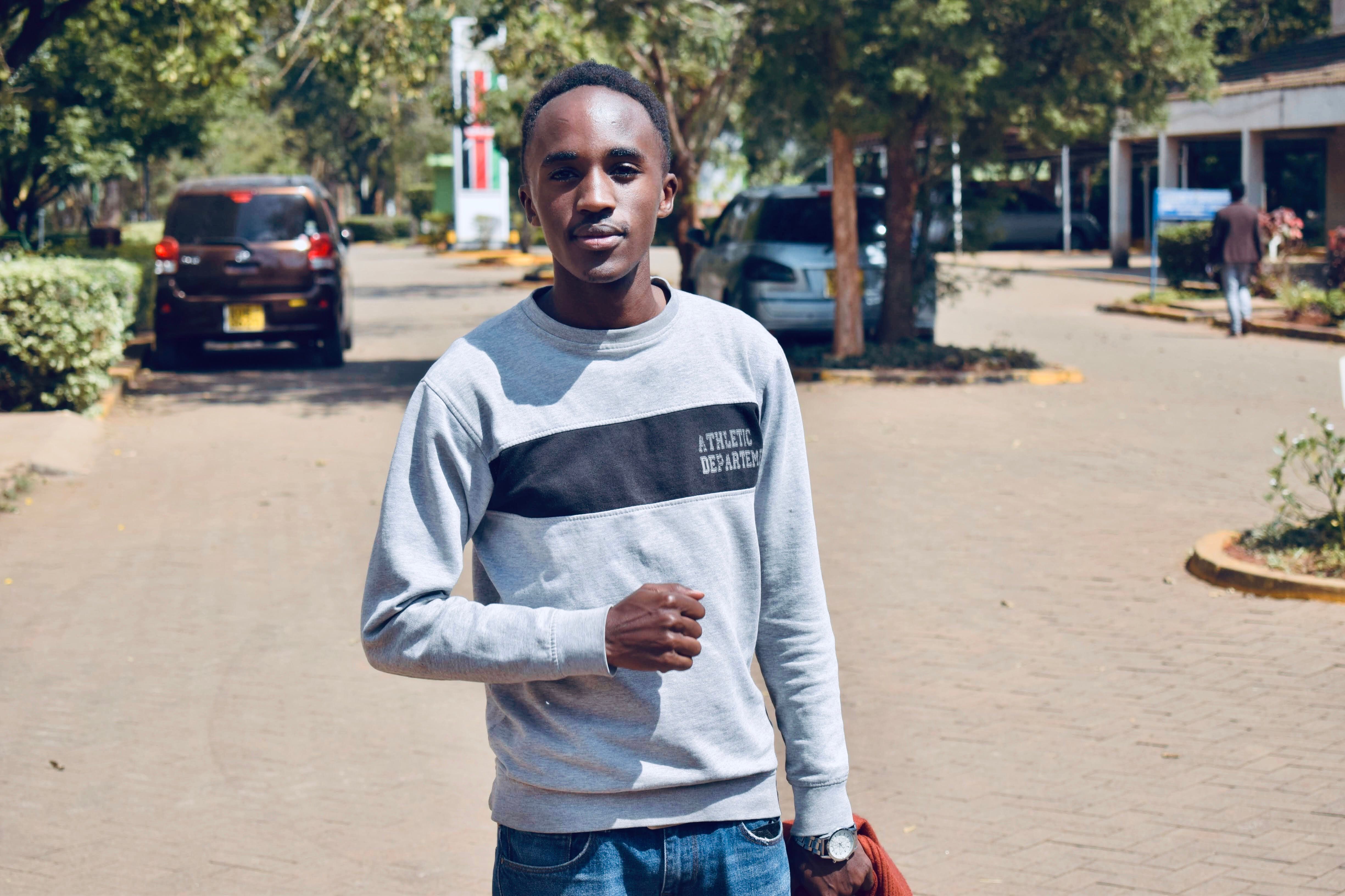 Stylish young man in a sweatshirt poses confidently in an outdoor urban setting.