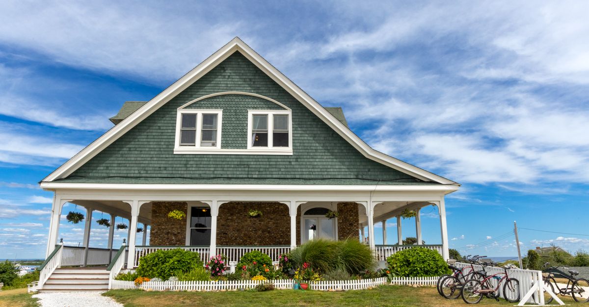 Idyllic house in Newport, RI surrounded by lush gardens and bicycles under a vibrant sky.