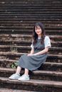 一位年轻女子身着便装，坐在户外楼梯上热情地微笑着