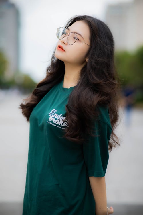 Woman in Green Oversized Shirt Wearing Eyeglasses while Posing at the Camera