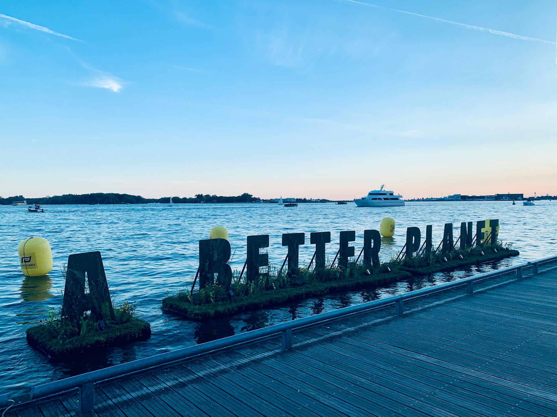 A scenic view of the Toronto waterfront with 'A Better Planet' sign promoting environmental awareness.