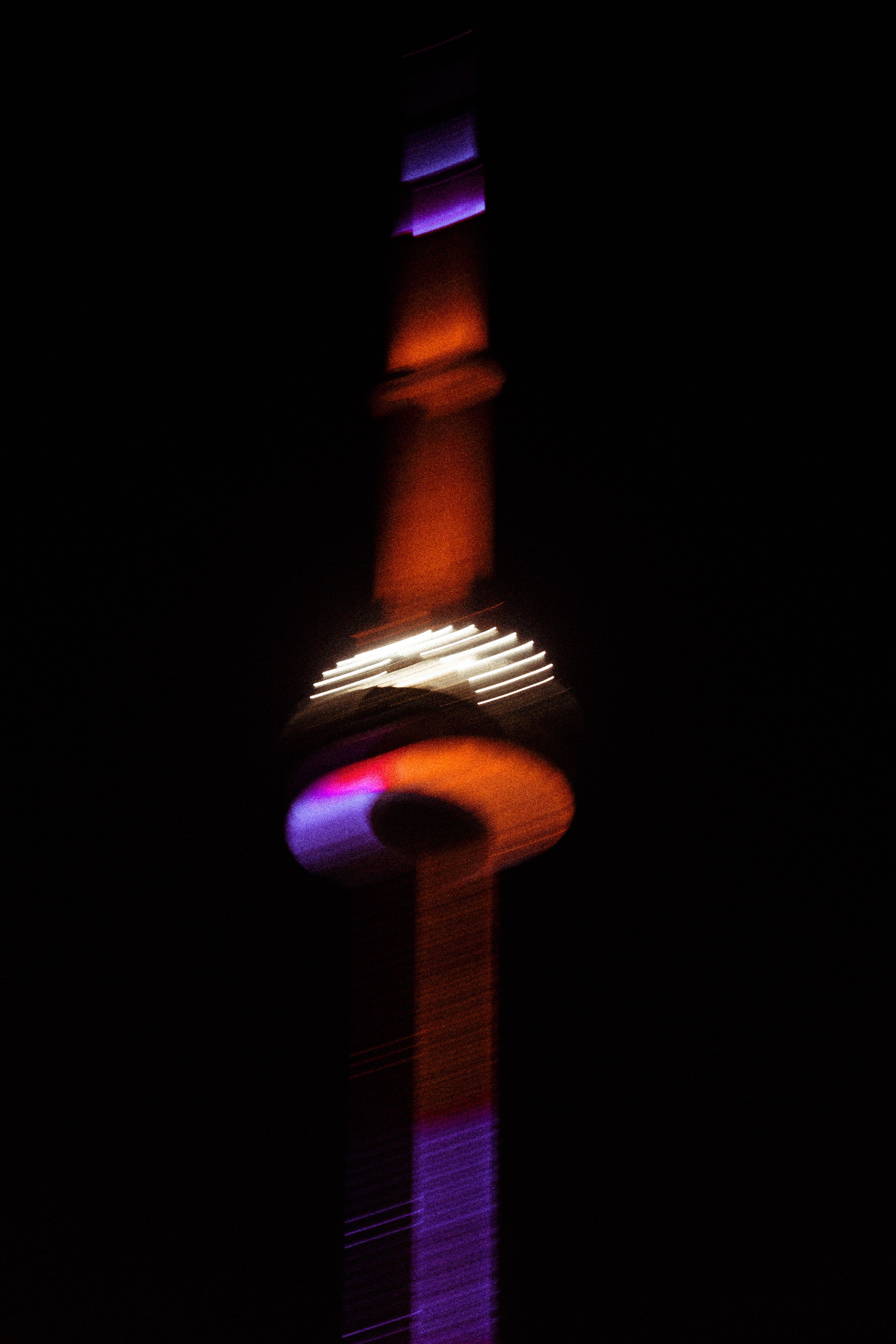 Abstract photo of the illuminated CN Tower at night in Toronto, showcasing vibrant colors.