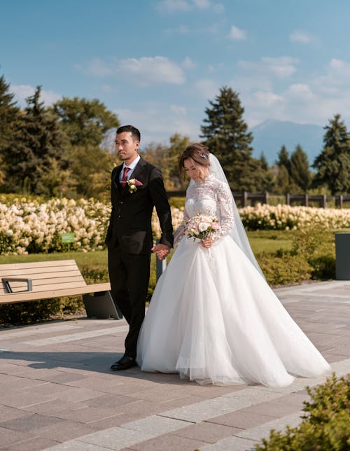Man and Woman in Wedding Dress Standing on Gray Concrete Pavement
