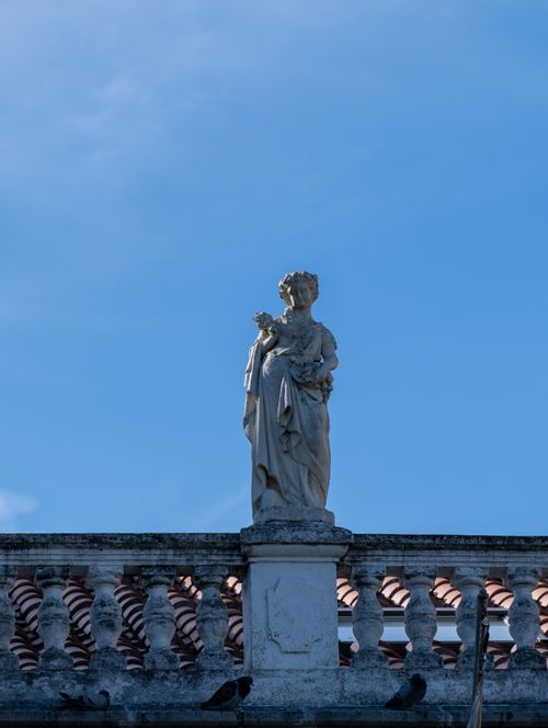 Free Ornate stone statue on ornate railing with clear blue sky backdrop, showcasing classic architecture. Stock Photo