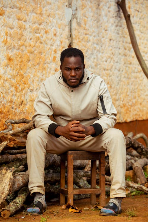 Man in Beige Jacket Sitting on Wooden Stool