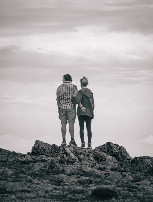 Woman and Man Standing on Rock in Black and White