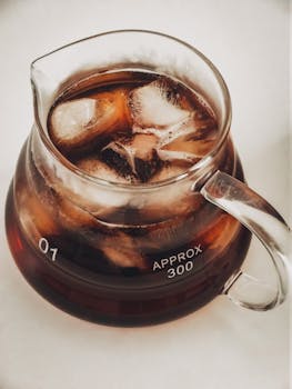 Close-up of iced coffee with ice cubes in a transparent glass carafe, perfect for a cool summer drink.