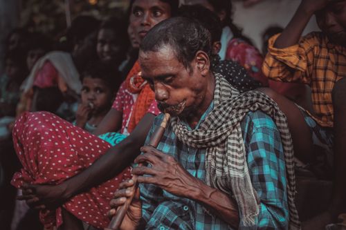 Free Indian musician playing a bansuri flute during a cultural gathering, showcasing traditional attire. Stock Photo