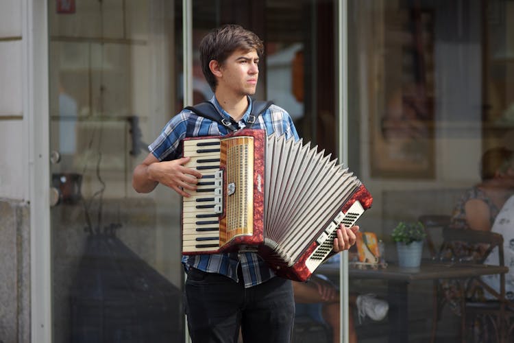 Man In Blue And White Plaid Polo Playing Red And White Accordion