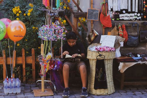 Free A boy reading amidst colorful street market stalls in Talas, Kayseri, Türkiye. Stock Photo