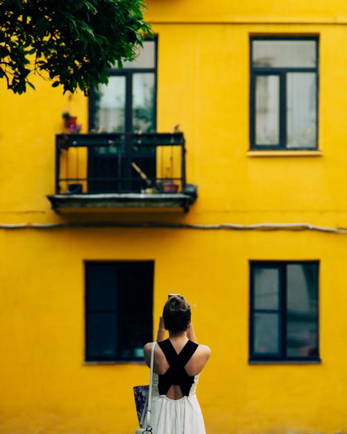 Back View of a Woman Taking Picture of a Yellow Building