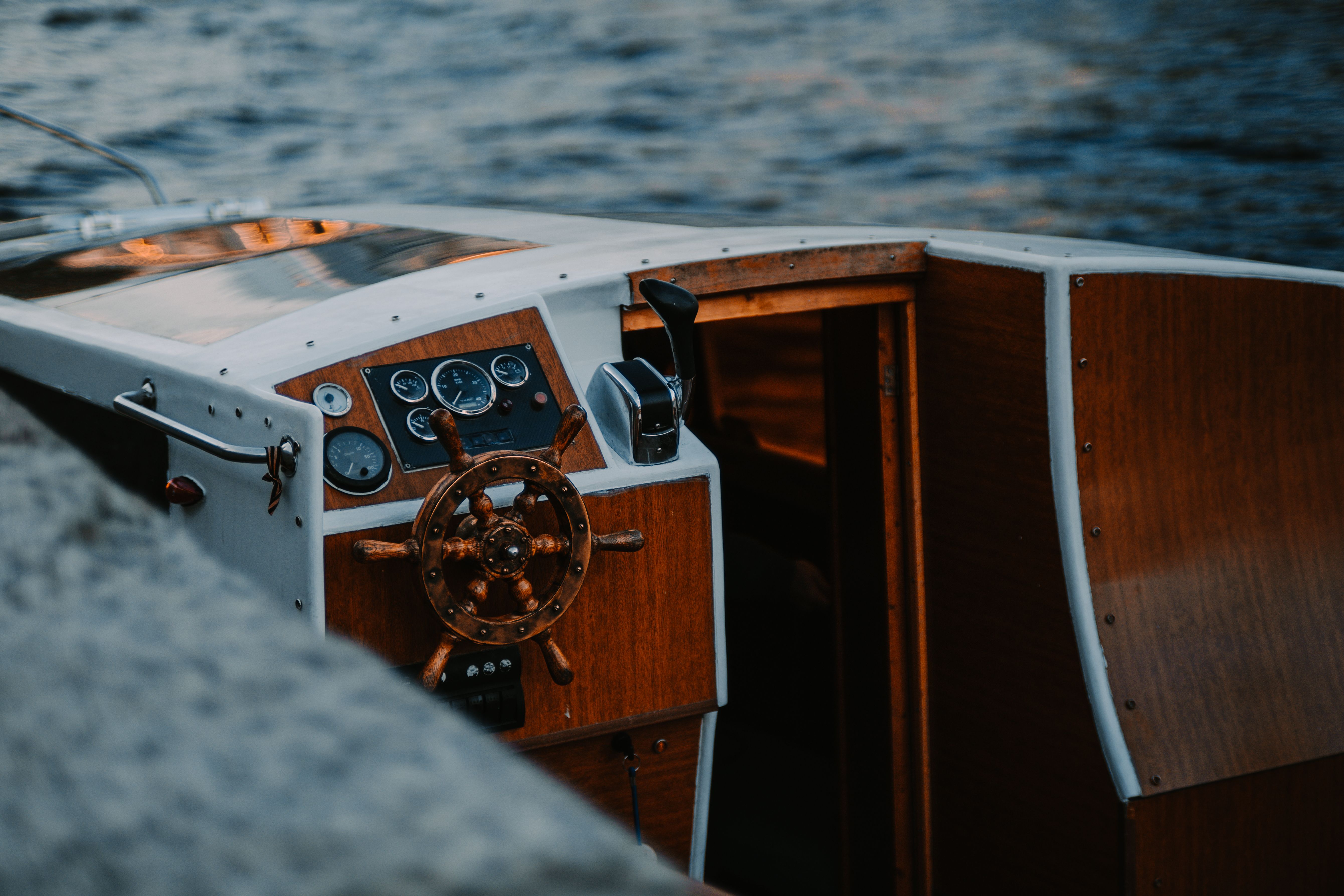 close-up of a wooden sailboat rudder guided by hand on a calm sea