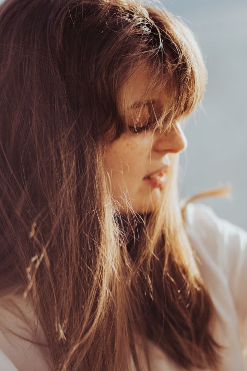 Free Warm, intimate close-up portrait of a woman with brown hair and soft light outdoors. Stock Photo