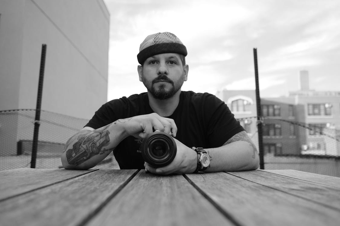 A Grayscale of a Bearded Man Holding a Camera