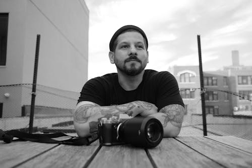 A Grayscale of a Bearded Man with a Camera