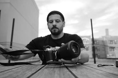 A Grayscale of a Bearded Man Holding a Camera