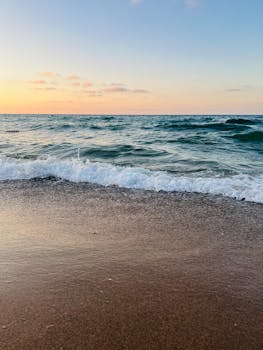 Peaceful scene of ocean waves at sunrise, capturing the tranquility of the sea shore.