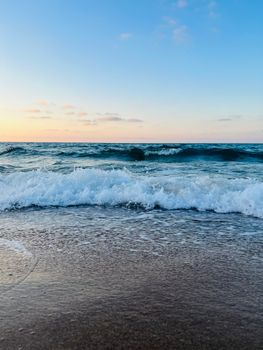 Peaceful beach scene at twilight with ocean waves crashing gently on the sandy shore.