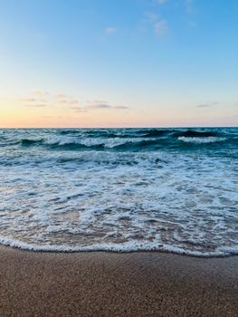 Peaceful ocean waves gently caressing the sandy beach at sunrise, creating a tranquil scene.