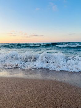 Experience the tranquility of ocean waves crashing gently on a sandy beach during a beautiful sunset.