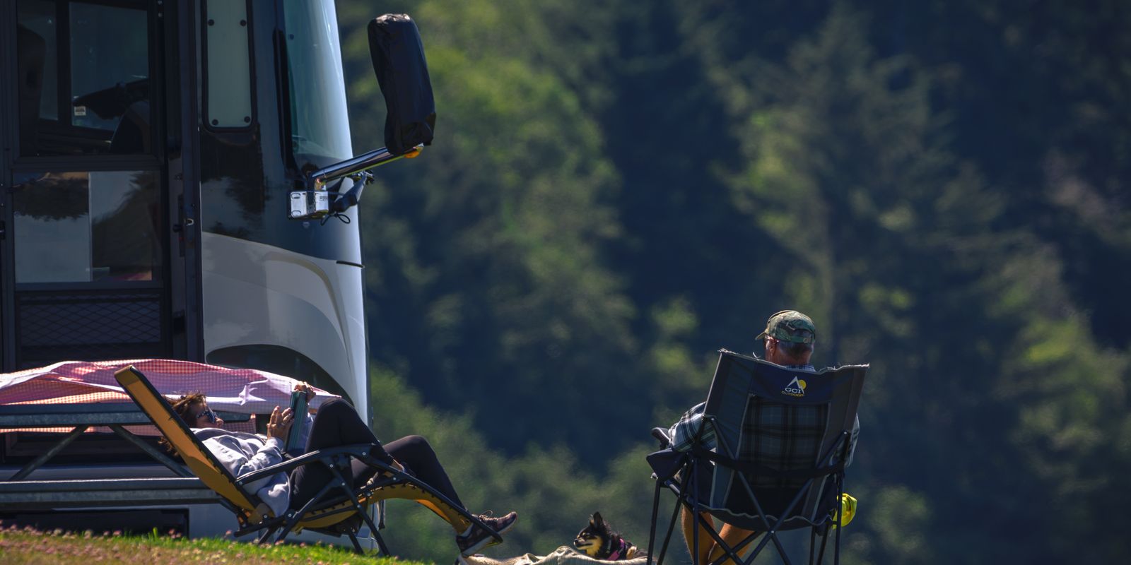 A couple relaxing outdoors beside their RV on a sunny day