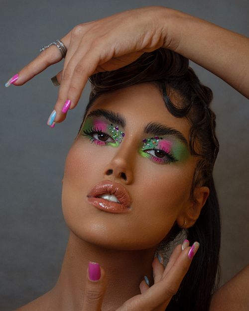 Free Close-up portrait showcasing vibrant makeup and colorful eyeshadow, featuring manicured nails. Stock Photo