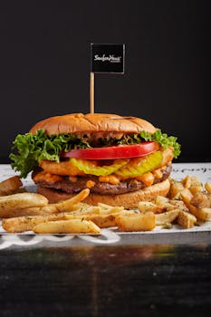 Tasty cheeseburger with crispy fries on black background, perfect for food lovers.