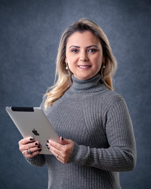 Close-Up Shot of a Woman in Gray Sweater Holding a Silver iPad