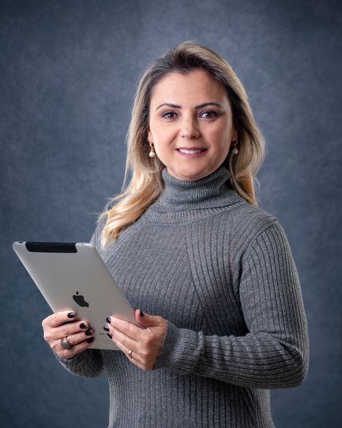 Free Caucasian woman in a gray sweater holding a tablet in a studio portrait setting. Stock Photo