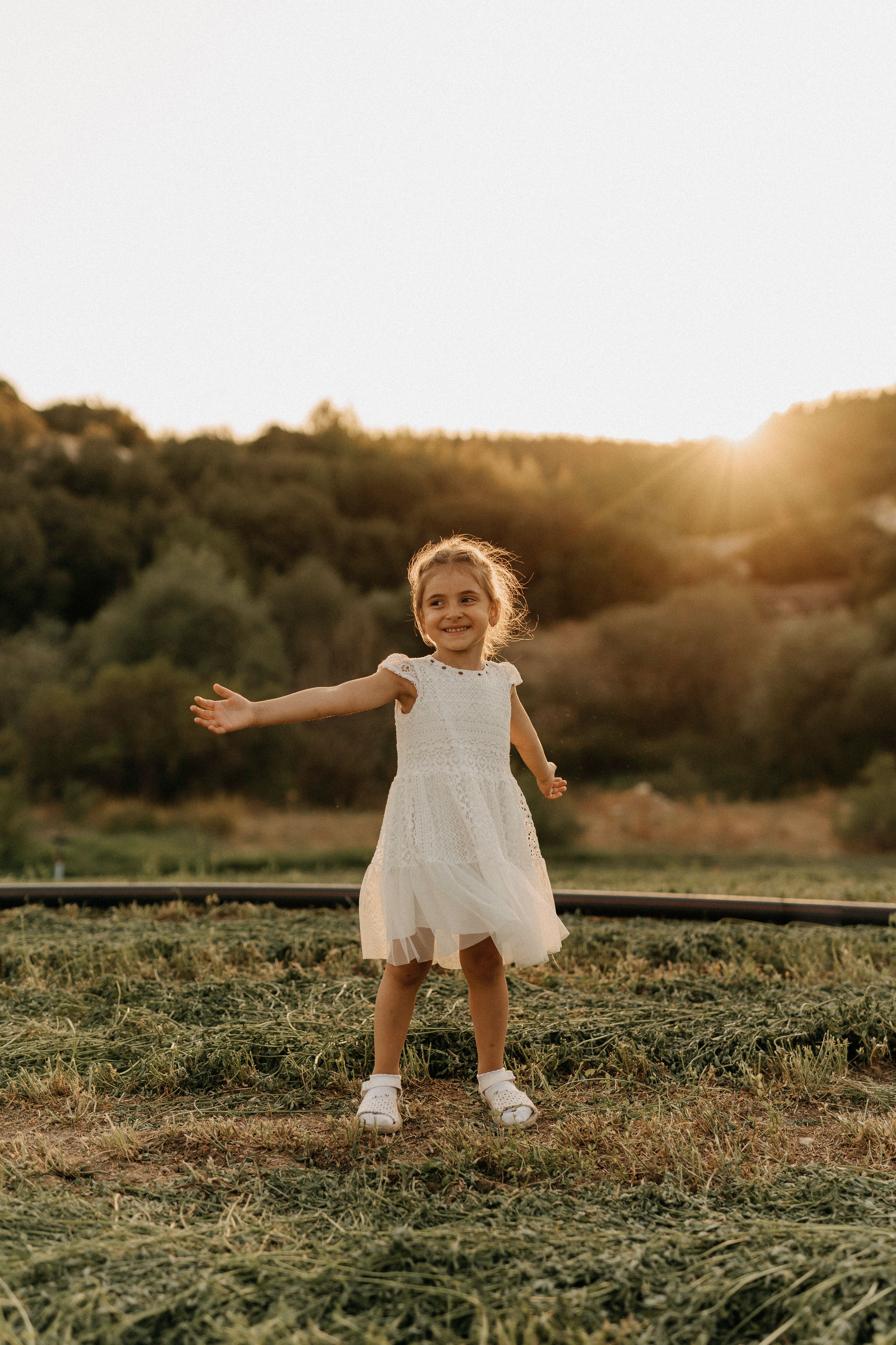 Little Girl in White Dress Standing on Green Grass · Free Stock Photo