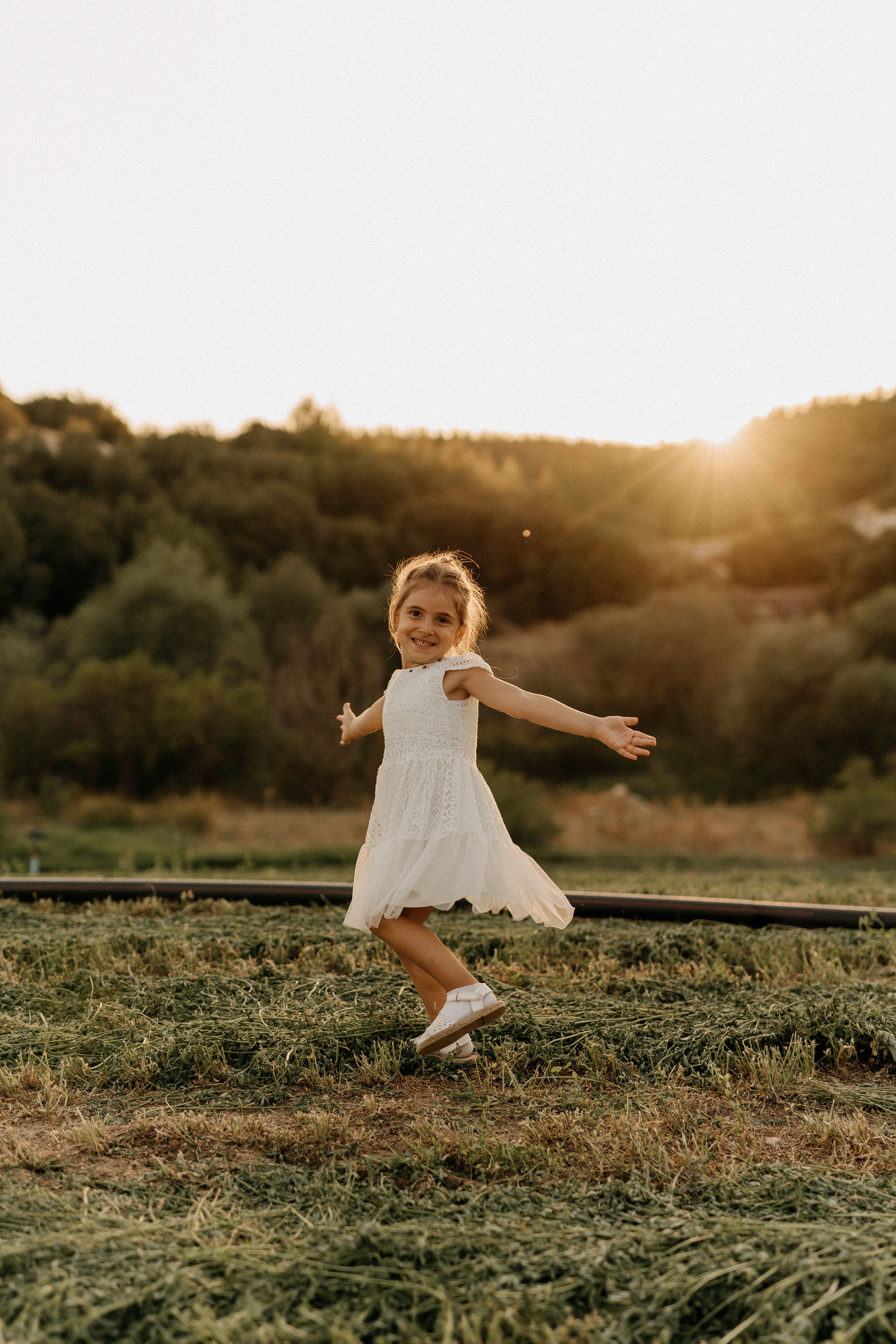 Little Girl in White Dress Standing on Green Grass · Free Stock Photo