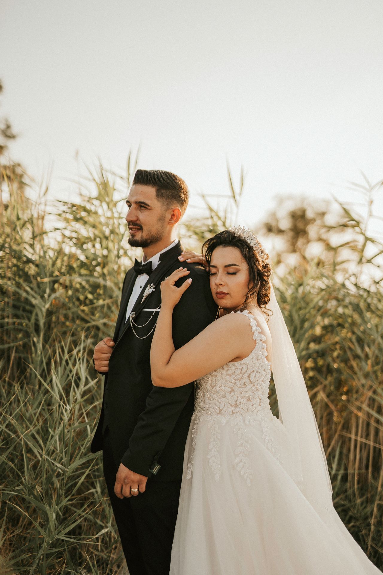 A romantic wedding portrait featuring a bride and groom embracing outdoors during the golden hour.