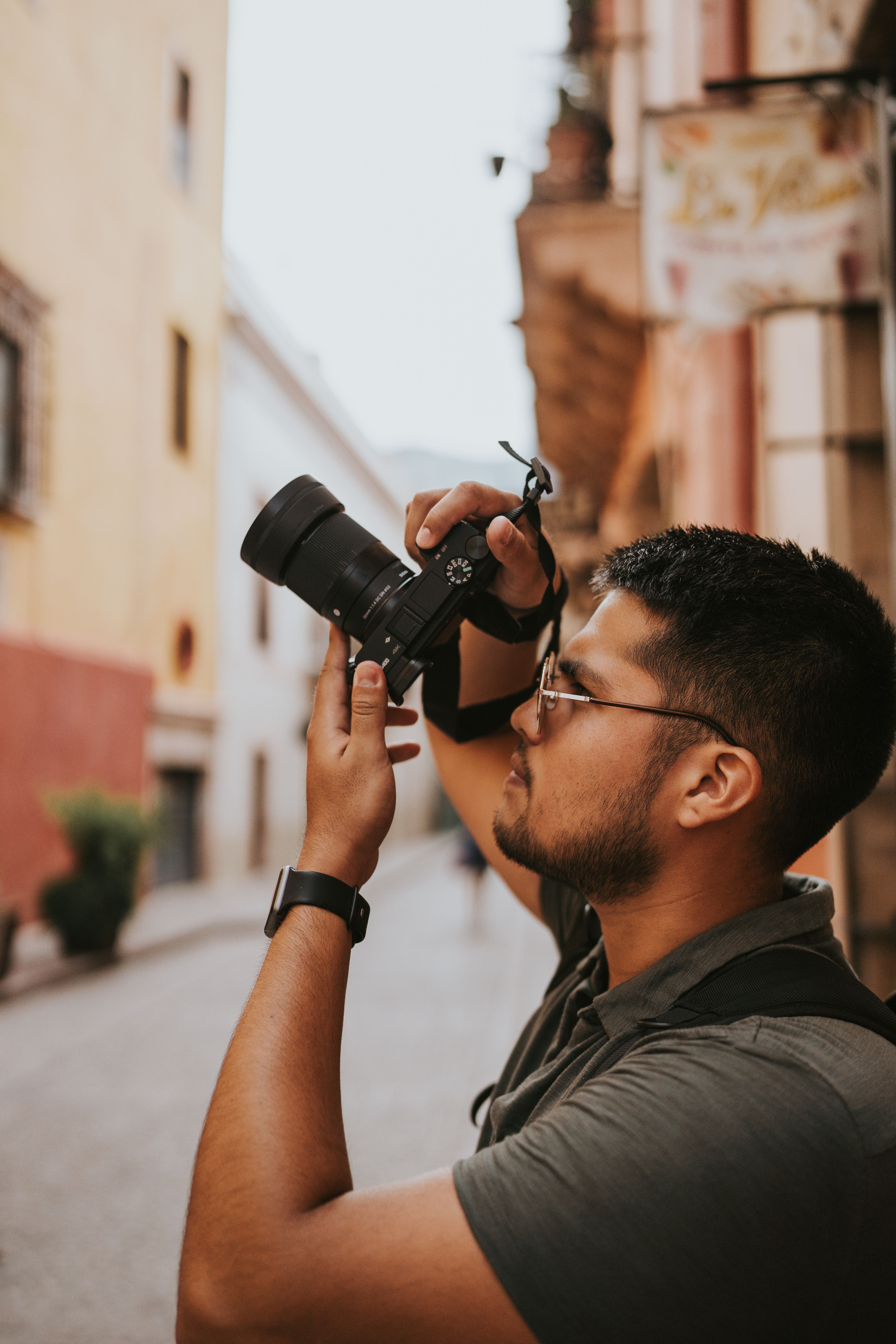 An adult male photographer captures a street scene in Guanajuato, Mexico.